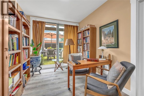 Study room with floor-to-ceiling bookshelves, desk, chairs, and artwork on the walls. - 442 Alexander Ave Avenue Unit# 201, Penticton