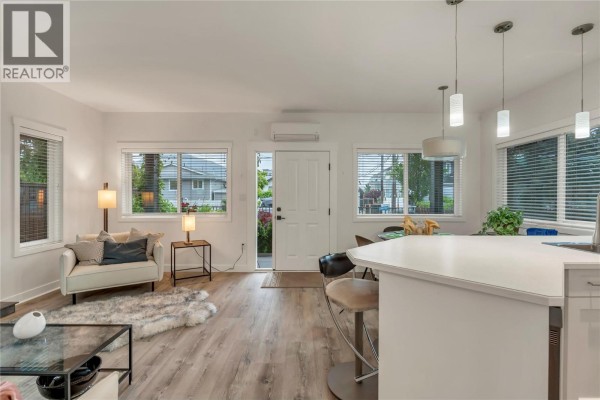 View of the living room, dining area, kitchen island, and exterior door. - 442 Alexander Avenue Unit# 101, Penticton