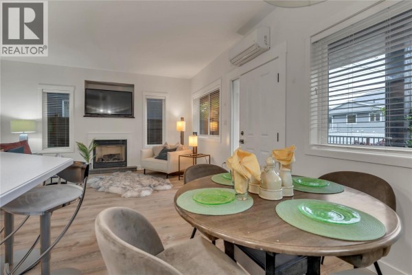 Dining table with green placemats and seating, adjacent to a kitchen island and living area. - 442 Alexander Avenue Unit# 101, Penticton