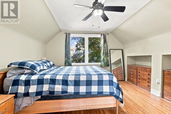 Bedroom with checkered bedding, wood floors, ceiling fan, and window view - 442 Grandview Avenue Wilmot