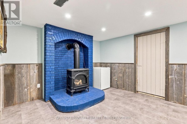 Wood-burning stove with blue brick hearth, mini-fridge, paneled walls - 442 Grandview Avenue Wilmot