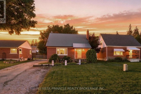 The red brick house at dusk with a colorful sunset sky and the lights on in the windows. - 442 Grandview Avenue, Wilmot