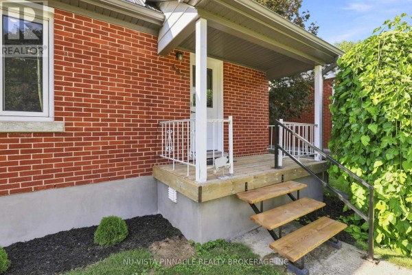 Close-up of the covered front porch with wooden steps, white railings, and red brick exterior. - 442 Grandview Avenue, Wilmot