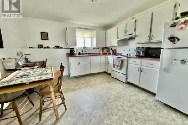 Kitchen with white cabinets, white appliances, a dining table, and chairs. - 442 Maddix Crescent, Summerside