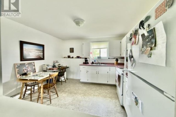 Kitchen featuring white cabinets, countertop, sink, refrigerator, and dining area. - 442 Maddix Crescent, Summerside