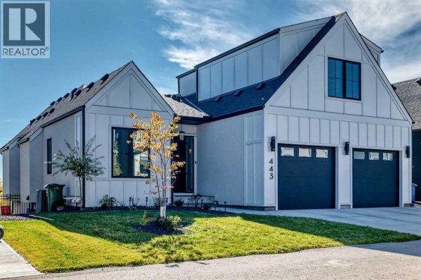 Side exterior view of a modern white house with a gabled roof and a double garage. - 443 Grayling Lane, Rural Rocky View County