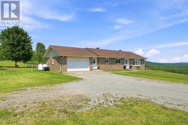 One-story stone house with garage on a gravel driveway, large lawn. - 443 Holland Lake Road, Bancroft
