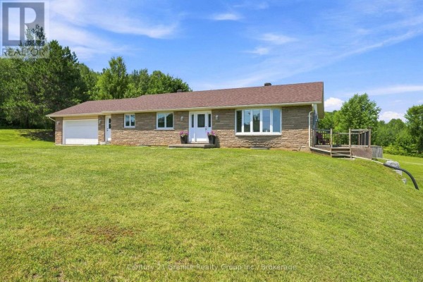 Side view of a one-story stone house on a grassy hill. - 443 Holland Lake Road, Bancroft