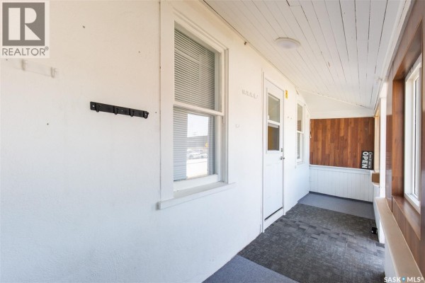 Interior sunroom with white walls, wood paneling, and a door leading outside. - 443 Lillooet Street W, Moose Jaw