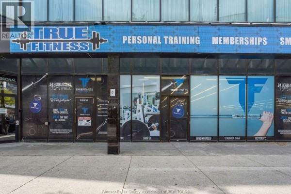 Close-up of the fitness center's storefront with gym branding and large glass windows. - 443 Ouellette Avenue, Windsor