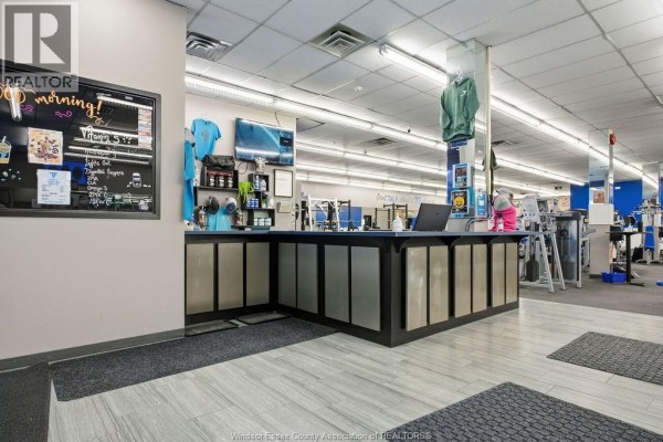 Reception desk inside a fitness center with a laptop, merchandise, and gym equipment. - 443 Ouellette Avenue, Windsor
