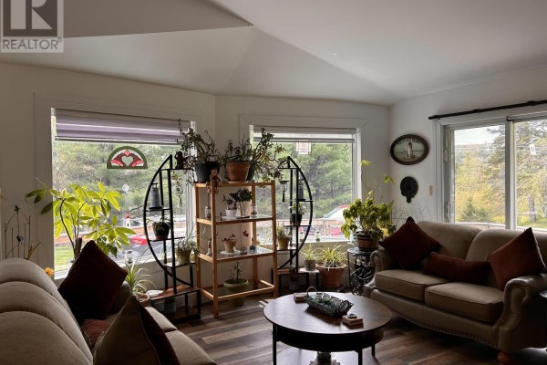 Living room featuring a wood-burning stove, stacked firewood, and comfortable seating with sofas and pillows. - 4430 252 Highway, Hillsboro
