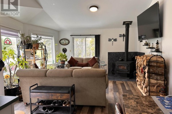 Living room with large windows offering views of trees, decorated with houseplants and two beige sofas. - 4430 252 Highway, Hillsboro