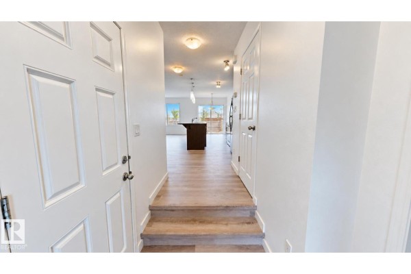 View from entrance into hallway with white walls and laminate flooring. - 4434 Prowse Rd Sw, Edmonton