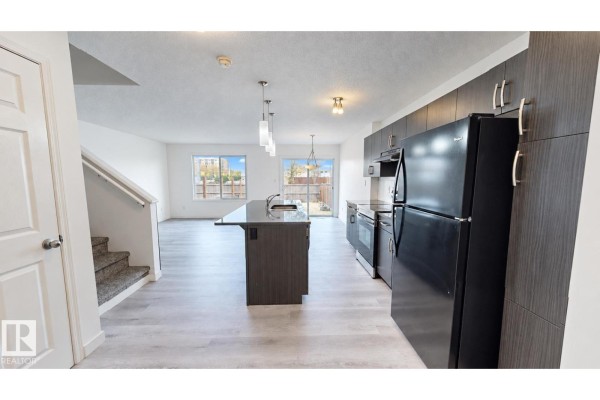 Kitchen with dark grey cabinets, black appliances, and a large island. - 4434 Prowse Rd Sw, Edmonton