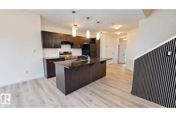 Kitchen and dining area with dark wood cabinets, granite island, and light laminate flooring. - 4434 Prowse Rd Sw, Edmonton