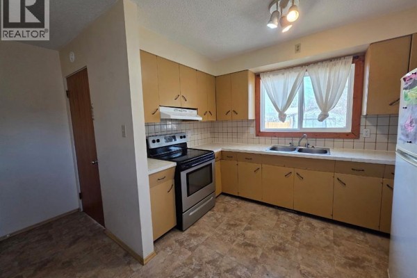 Bedroom with wood flooring, a bed, dresser, and television. - 4436 51st Avenue, High Prairie
