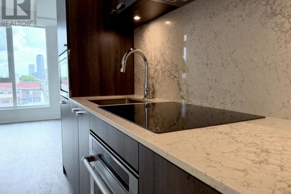 Detail of a kitchen counter with a dual sink, induction cooktop, and marble backsplash. - 444 - 858 Dupont Street, Toronto
