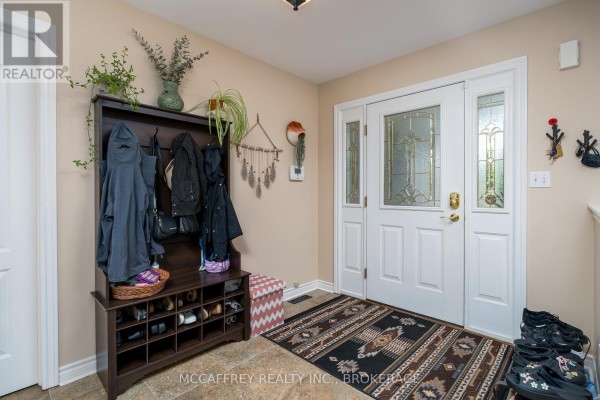 Interior entryway with a dark wood hall tree, shoe rack, patterned rug, and double doors. - 444 Bridge Street W, Greater Napanee