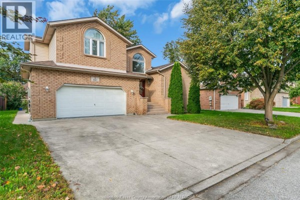 Exterior view of a brick house with a double garage door and driveway. - 445 John Harvey Crescent, Windsor