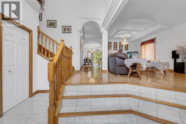 Interior foyer with a wooden staircase, tiled floor, and an open living room. - 445 John Harvey Crescent, Windsor