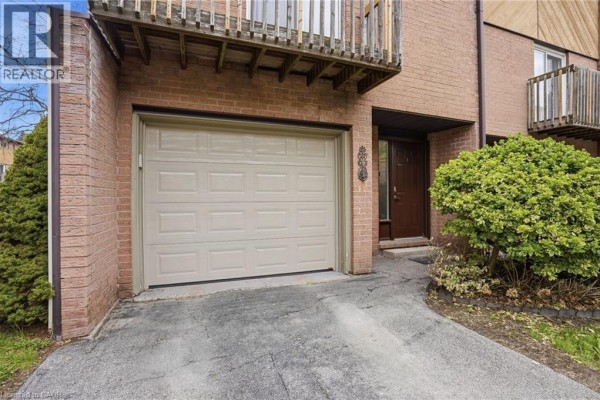 Close-up of garage door and front entrance of brick townhouse. - 445 Stone Church Road W Unit# 19, Hamilton
