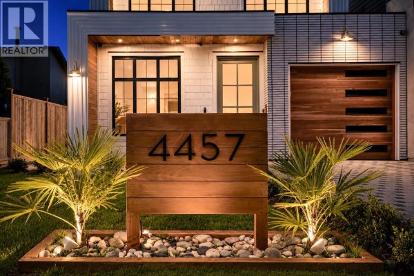 Close-up of the wooden address marker '4457' in front of a duplex home with modern landscaping. - 4457 46a Street, Delta
