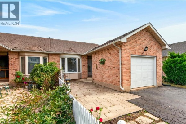 Front view of the brick townhouse showing the entrance, patio, and bay window. - 4459 Christopher Court, Beamsville