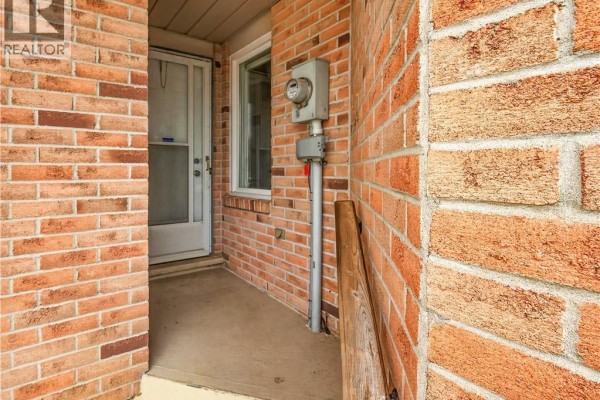 Close-up of the brick exterior wall, electrical meter, and front door of the townhouse. - 4459 Christopher Court, Beamsville