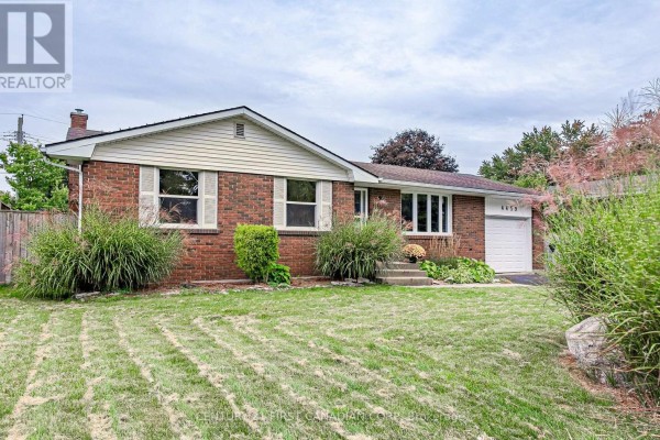 Close-up exterior view of brick bungalow with bay window and manicured landscaping. - 4459 Hamilton Road, Thames Centre