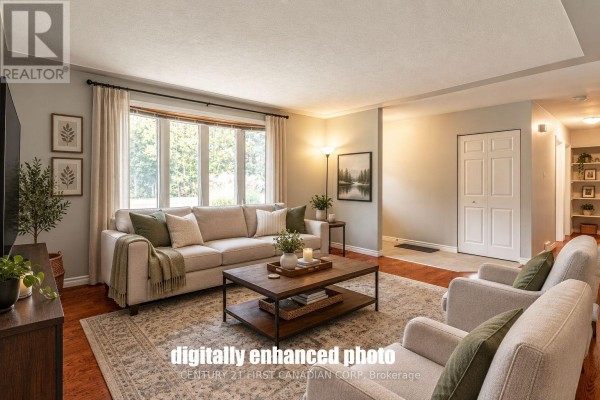 Living room with beige sofa, dark wood coffee table, and hardwood floors. - 4459 Hamilton Road, Thames Centre