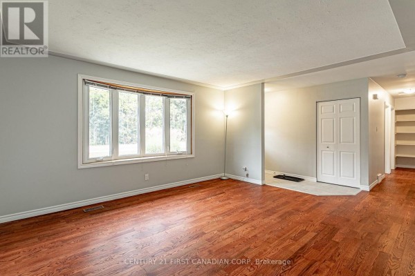 Living room with hardwood floors, neutral walls, and a large bay window. - 4459 Hamilton Road, Thames Centre