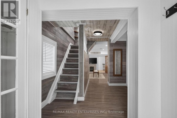 Interior view of a staircase and living room with wood-paneled walls and a fireplace. - 446 Cambridge Road W, Fort Erie