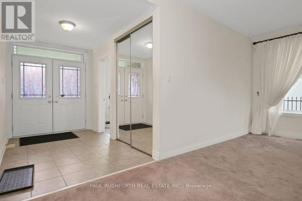 Interior foyer with beige tile floor, mirrored closet doors, and cream walls. - 446 Frank Cauley Way, Ottawa
