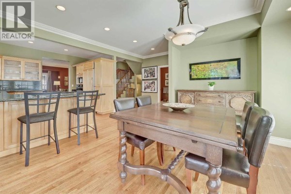 Dining area adjacent to kitchen, featuring a wooden table and leather chairs. - 446 Killarney Glen Court Sw, Calgary