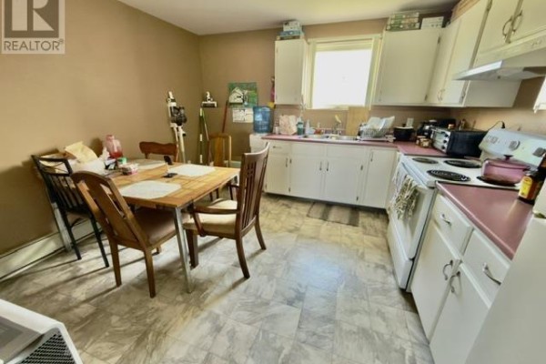 Kitchen area with white cabinets, sink, stove, and a dining table. - 446 Maddix Crescent, Summerside
