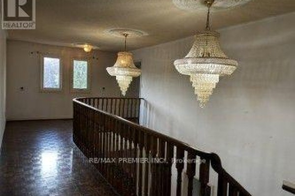 Hallway with ornate chandeliers and dark wood railing - 4464 Stonemill Court Mississauga
