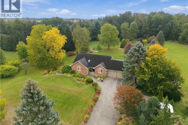 Drone view of a brick house with a paved driveway, manicured lawn, and lush green surroundings. - 447 King Edward Street, Paris