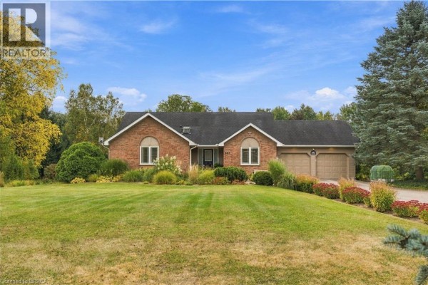 Front exterior of a single-story brick house with a green lawn, landscaped garden, and double garage. - 447 King Edward Street, Paris