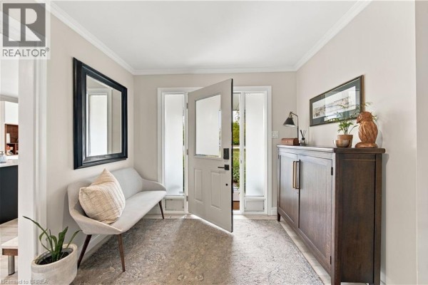 Foyer with a light grey bench, large mirror, wooden cabinet, and an open front door. - 447 King Edward Street, Paris