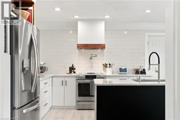 Modern kitchen with white subway tile backsplash, stainless steel appliances, and a black island. - 447 King Edward Street, Paris