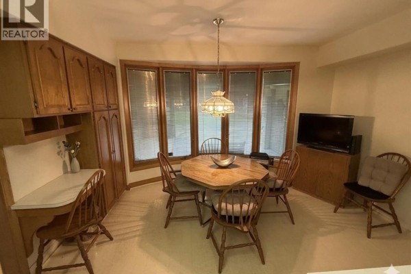 Dining room with octagonal table, bay window, and wooden cabinets - 4470 Riverside Windsor