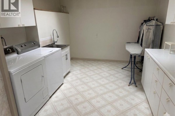 Laundry room with washer, dryer, sink, ironing board, and clothes rack - 4470 Riverside Windsor