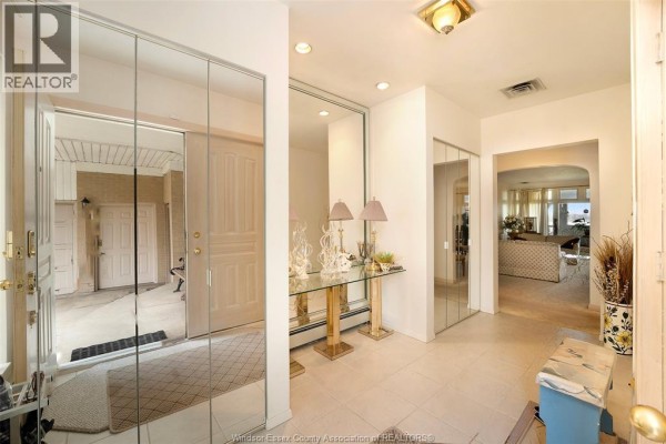 Interior entryway with mirrored closet doors, a glass console table, and tiled floor. - 4470 Riverside Drive, Windsor