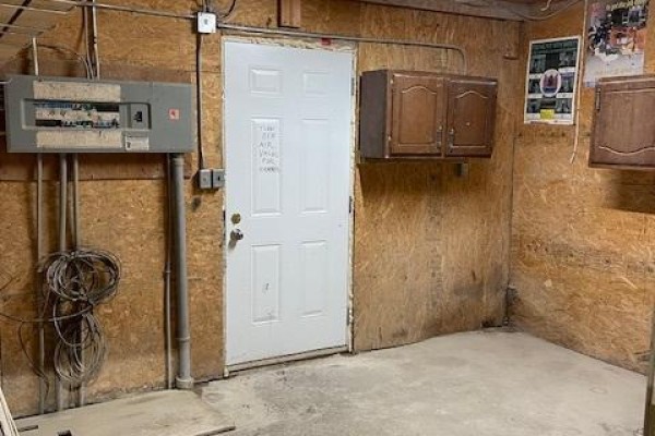Interior view showing a white door, wood paneling, electrical panel, and two wooden cabinets. - 44726 Line 34 Line, Huron East
