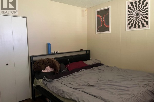 Bedroom with a metal-frame bed, two posters on the wall, and a white bi-fold closet. - 4475 Byng Rd, Port Hardy
