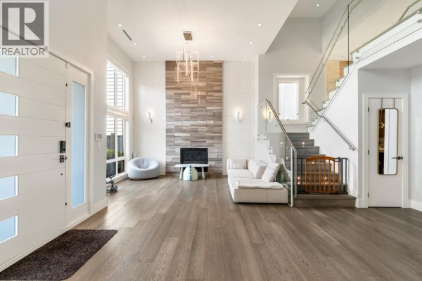 A wooden balcony with glass railings overlooks a lush green garden and trees. - 4480 Lancelot Drive, Richmond