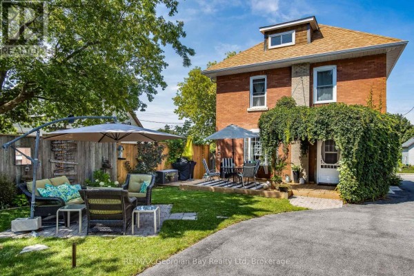 Backyard patio area with outdoor furniture, umbrellas, and a fenced yard. - 449 Elizabeth Street, Midland