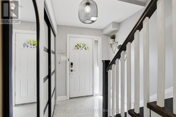 Foyer with white front door, reflective closet doors, and staircase with dark wood railing. - 45 - 4101 Westminster Place, Mississauga