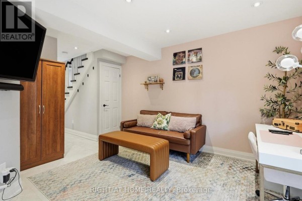 Den with brown sofa, ottoman, desk, and large wooden cabinet next to a staircase. - 45 - 4101 Westminster Place, Mississauga